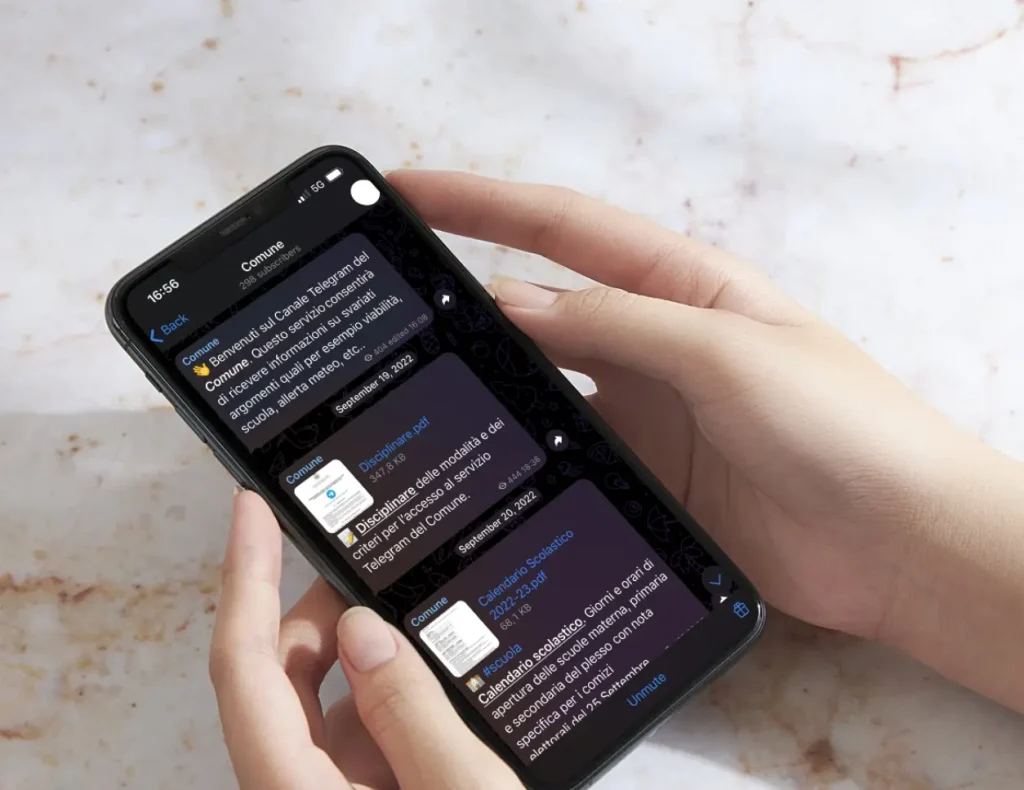 Telegram-Chat einer Gemeinde, geöffnet auf einem Smartphone mit Marmorhintergrund, für den Service der Digital Agency Jinni S.r.l.