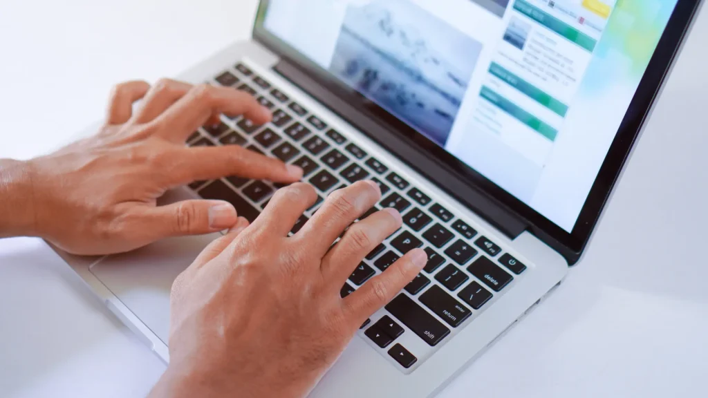 Manos de hombre tecleando en un portátil escribiendo contenidos para la web