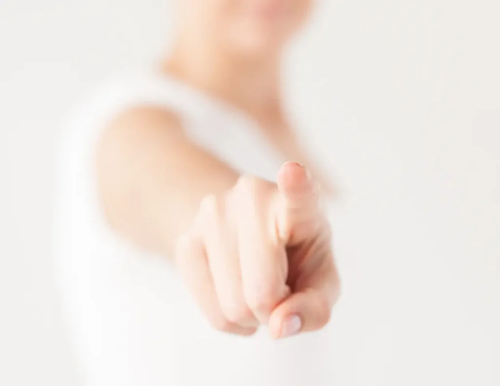 Hand, die auf das Ziel zeigt, mit unscharfem, hellem Hintergrund.