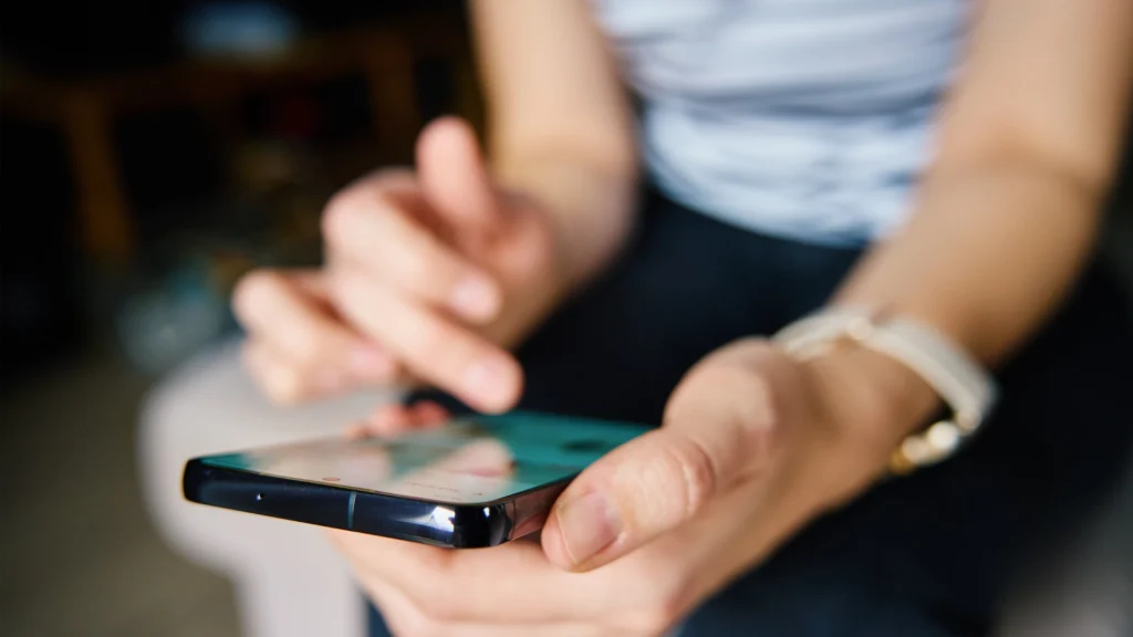 Primer plano de las manos de una persona que desliza con el pulgar la pantalla de un smartphone, para el artículo sobre formatos de redes sociales