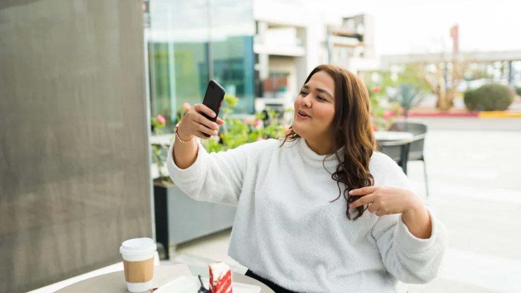 Persona sentada al aire libre con un smartphone en la mano que habla hacia la cámara para la story, para el artículo sobre formatos de redes sociales