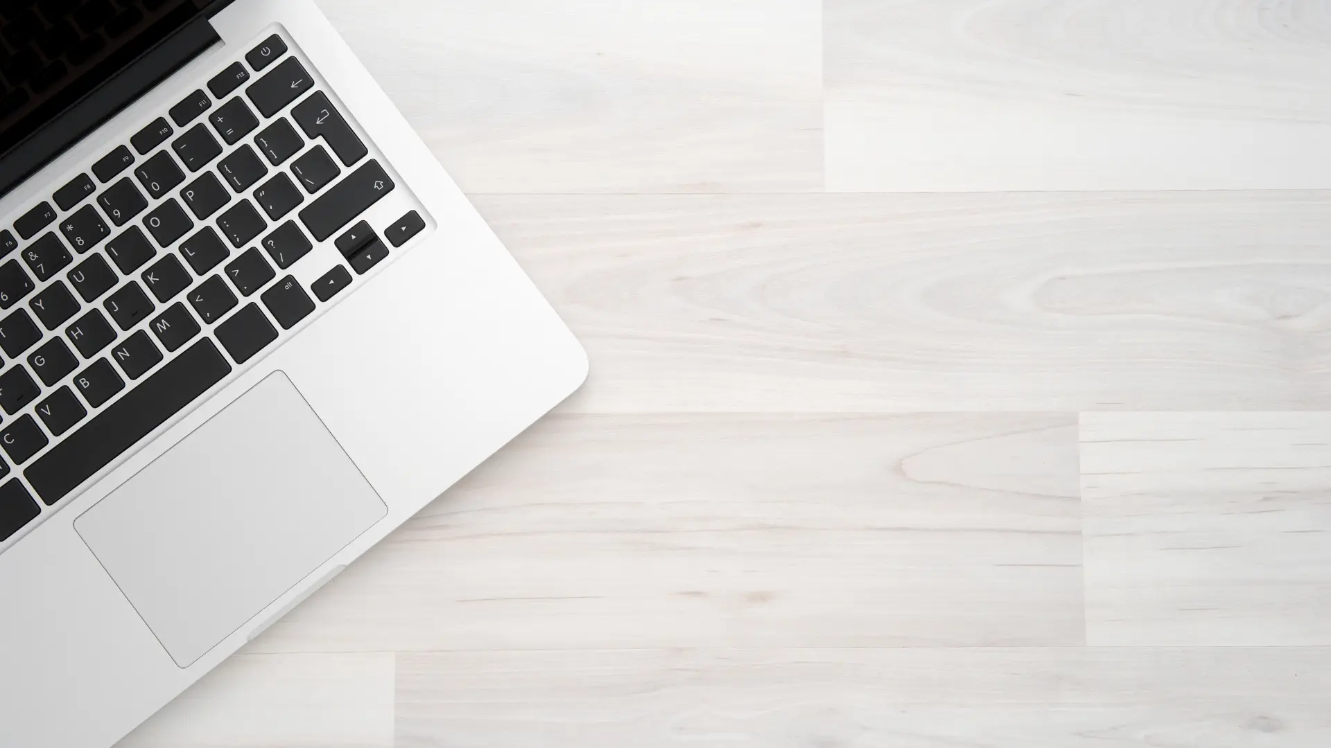 Vista dall’alto di un laptop parzialmente visibile su sfondo in legno chiaro per l'articolo dedicato alle soluzioni per migliorare le prestazioni del sito web.