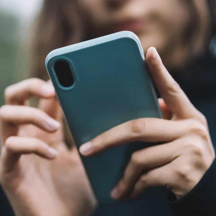 Ragazza con smartphone in mano su sfondo sfocato per il concetto di errori comuni nella gestione dei social media