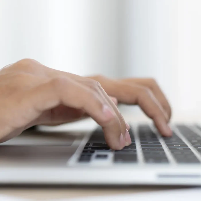 Mani che digitano sulla tastiera di un computer portatile per identificare i motivi per avere un sito web nel 2025