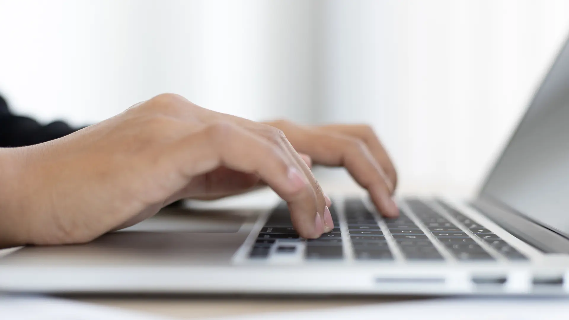 Mani che digitano sulla tastiera di un computer portatile per identificare i motivi per avere un sito web nel 2025