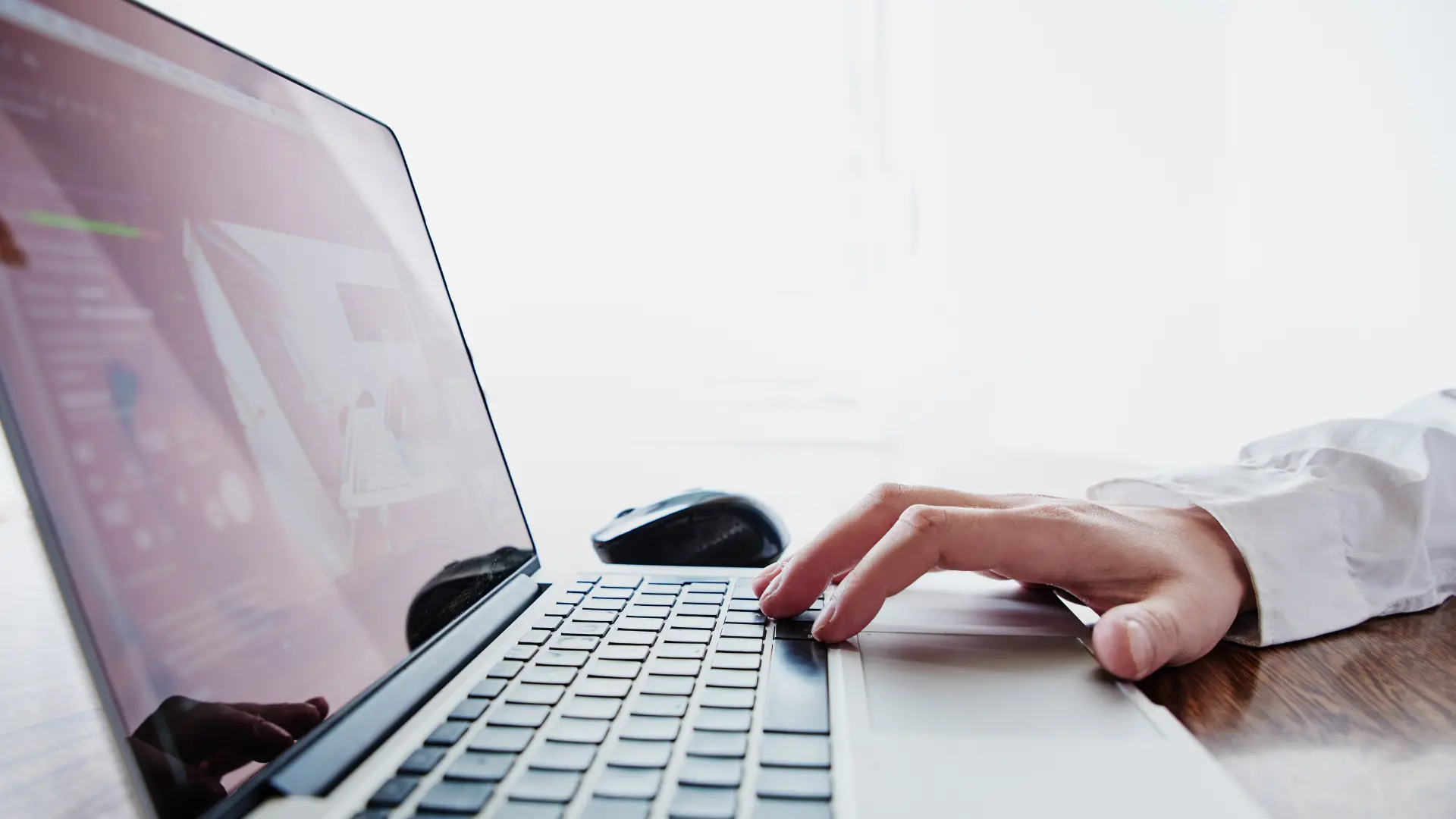 Mano che digita su un laptop con schermo riflettente per articolo 5 motivi per avere un sito web nel 2025