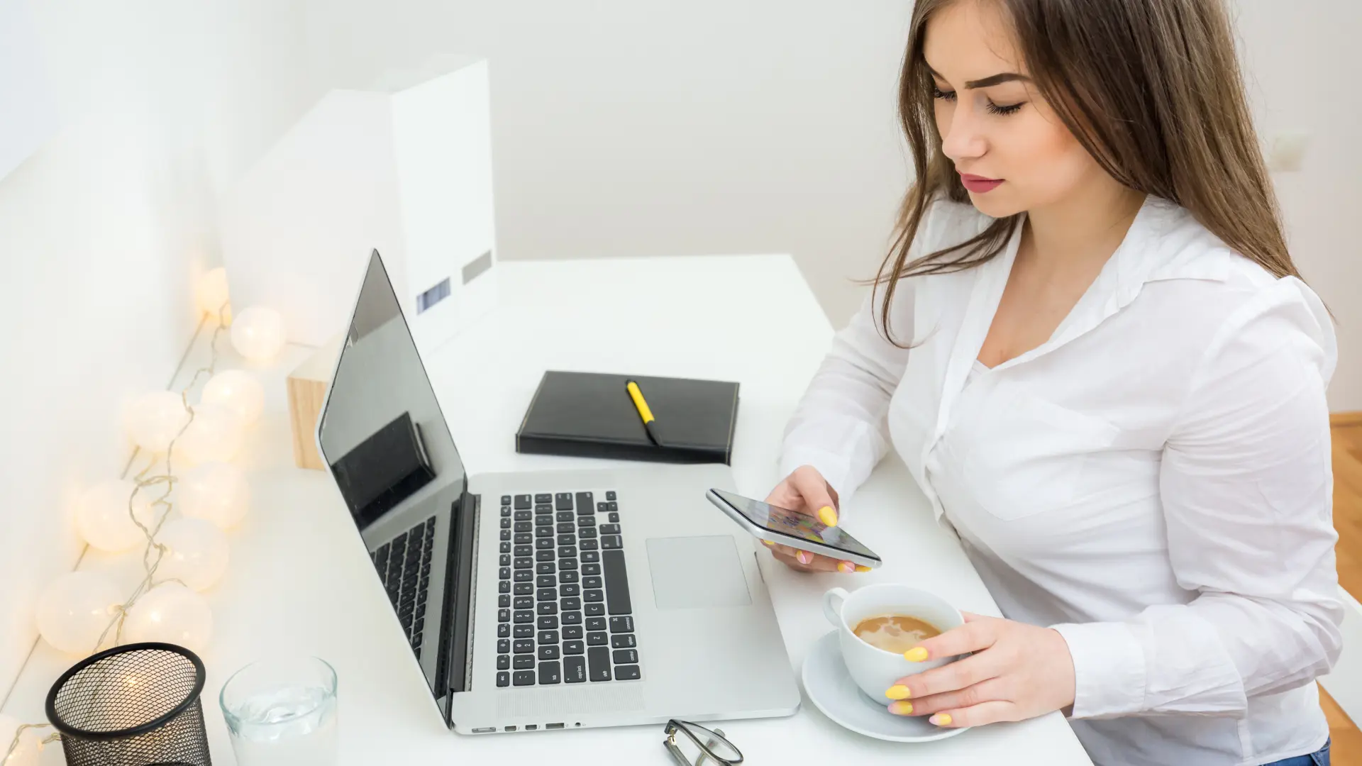 Donna lavora al computer con caffè e smartphone in mano per la guida sulle principali tipologie di contenuti per i social media.