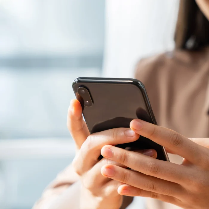 Primo piano di una mano che tiene uno smartphone, visibile un sorriso sul volto della persona per l'articolo sui formati social media