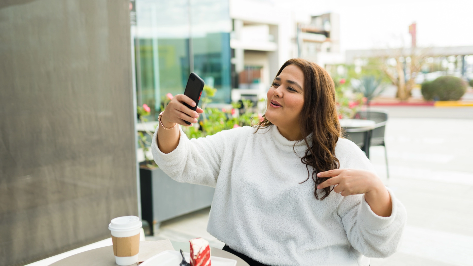 Person sitting outdoors holding a smartphone in hand and talking towards the camera for story for article on social media formats