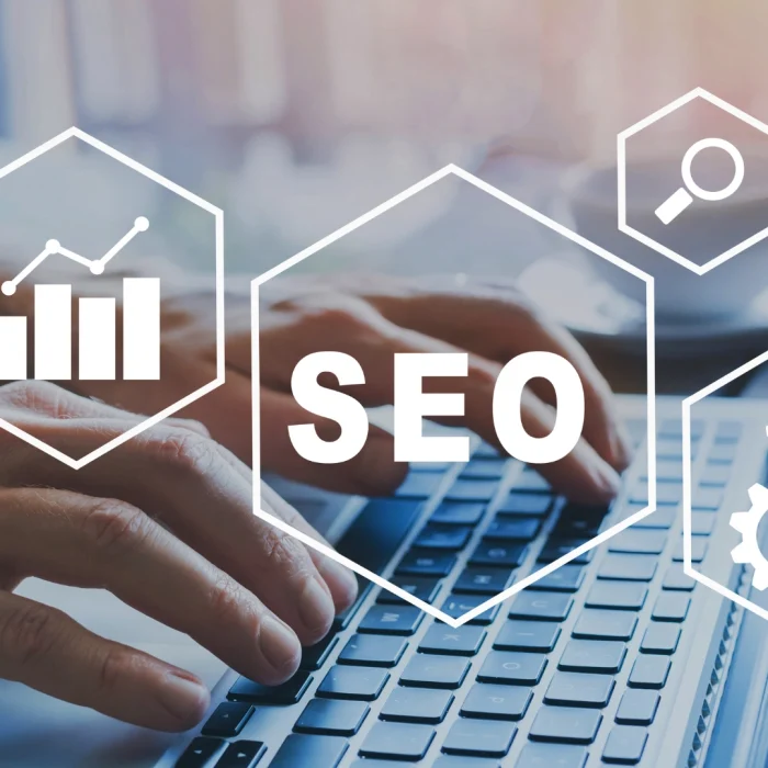 Mani su tastiera laptop con icone grafiche SEO: crescita, ingranaggi, ricerca e target