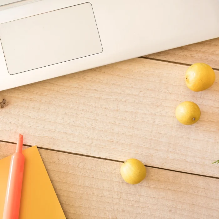 Summer desk with laptop, citrus fruits and notepad: symbol of light work and smart automations for the holidays.