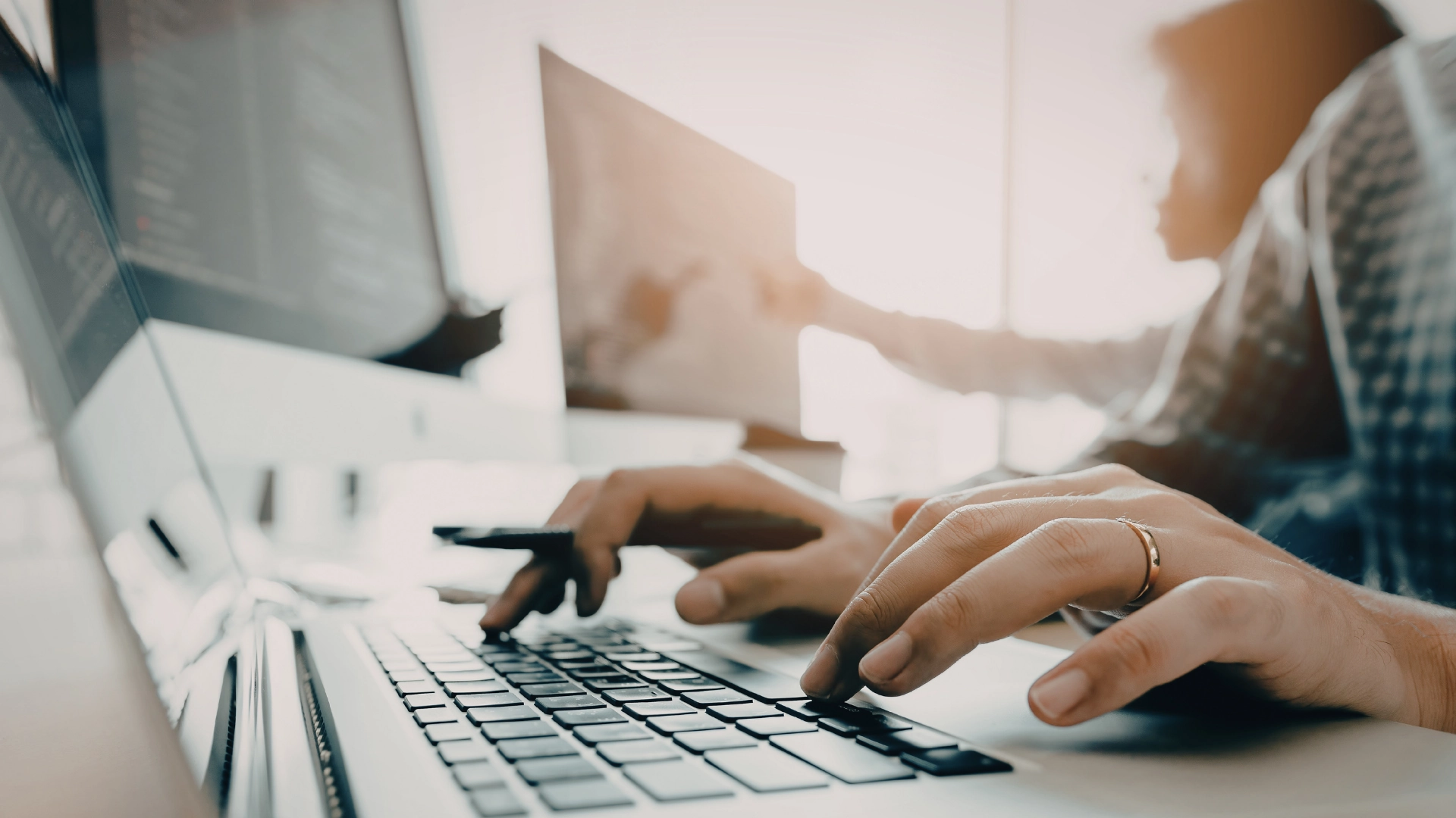 Persona che lavora al computer con le mani sulla tastiera in un contesto digitale