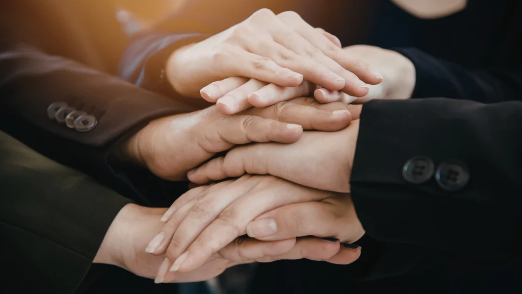 Mani sovrapposte di un team che rappresentano collaborazione e strategia condivisa