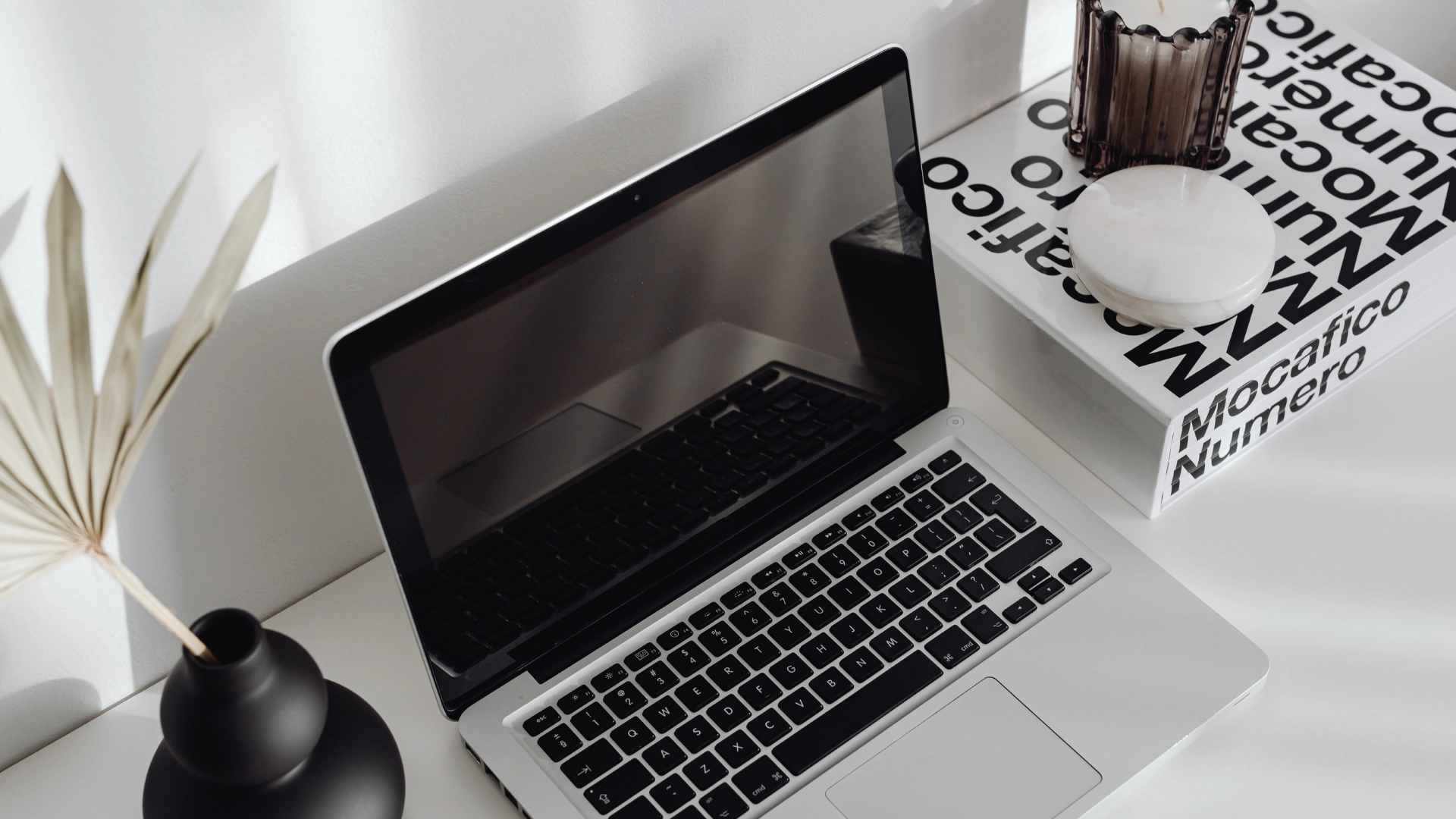Laptop su scrivania minimal con libri di marketing e design